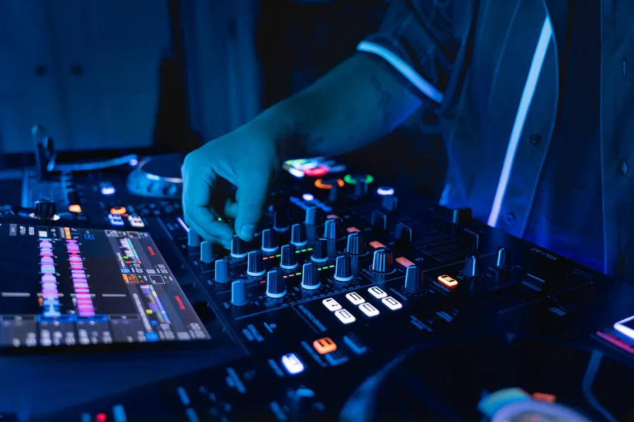 Close-up of DJ mixer and controls with blue lighting