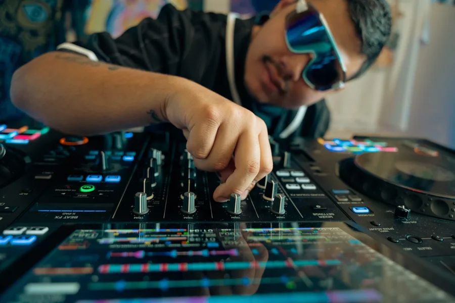 Close-up angle of DJ adjusting mixer with blue sunglasses